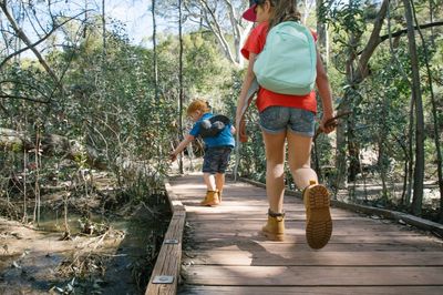 Two children walking along a boardwalk through bushland.