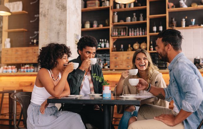 A group of friends laughing while drinking coffee at a cafe