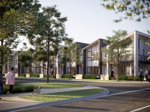 A row of modern townhomes at Riverlea along a calm tree-lined street on a bright, clear day. Pedestrians are walking along the wide footpaths alongside the streets.