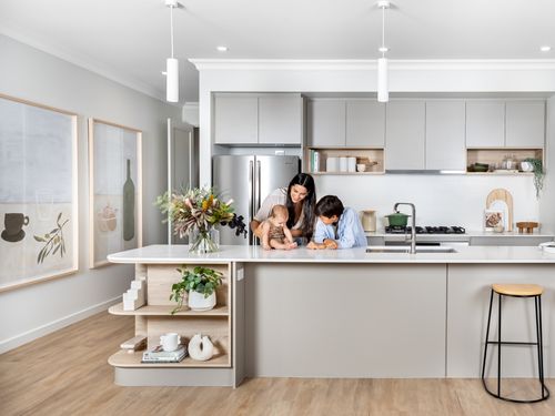 A parent with their child and baby spending time together in the modern kitchen of their new home.