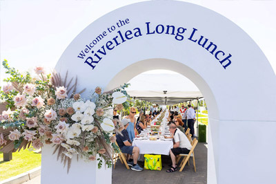 Residents sitting at a long table during Riverleas Long Lunch event.