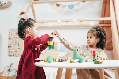 Two young children playing with wooden children’s toys