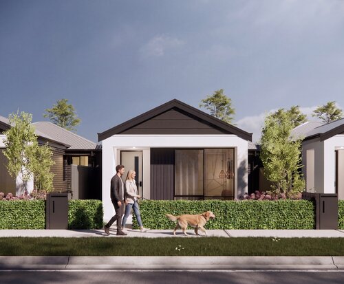 A row of modern single-storey terrace homes lines a quiet street while a couple walk their dog along the footpath under a bright sky.