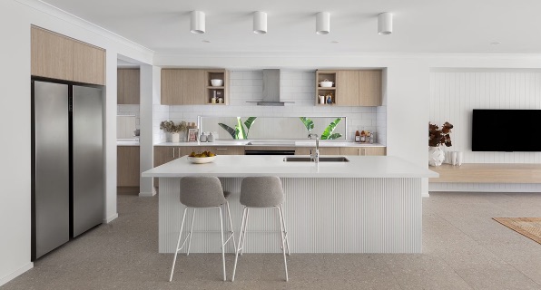 A designer coffee table holding light-coloured pottery standing in front of a wide sofa in a well-lit and well-designed modern living room.